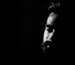 Captivating black and white portrait highlighting a man's thoughtful expression in deep shadows.